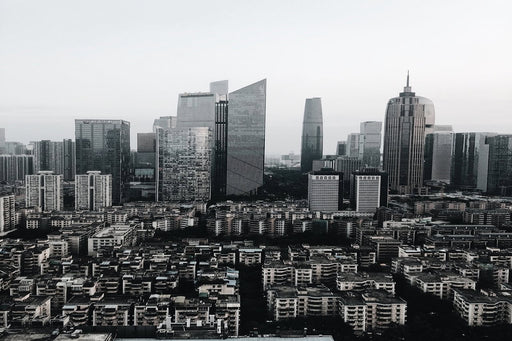 Vertical grayscale shot of an urban area with many high rise buildings of different shapes